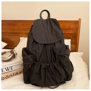Detail of the black pleated nylon backpack showing drawstring closure and side pockets