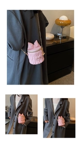 Détail de mini sac seau matelassé rose avec nœud décoratif et bandoulière chaîne