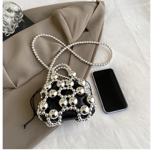 Close-up of a mini pearl bucket bag featuring silver metallic beads and black inner lining