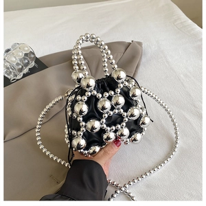 Detail of black drawstring bucket bag with silver mirror beads and beaded handle strap