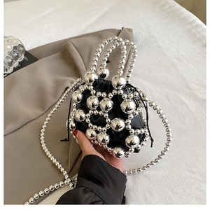Close-up of silver beaded drawstring bucket bag with black inner pouch and chain strap
