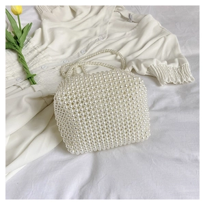 Detailaufnahme einer handgefertigten weißen Perlen-Handtasche mit eleganten Perlen-Griffen