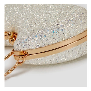 Macro view of heart-shaped evening bag with silver sequins and gold metal frame details