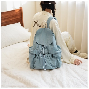 Detail of light blue nylon backpack with drawstring closure and side zipper pocket