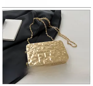 Detail shot of golden acrylic evening bag with cracked texture and chic metal chain