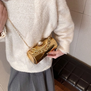 Glossy gold cylinder acrylic bag with chunky chain and pearl clasp shown on model