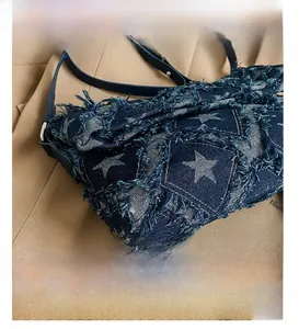 Detail presentation of dark blue denim bag with distressed star pattern texture