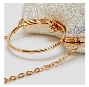 Macro shot of silver sequined evening bag featuring gold round handle and spherical clasp