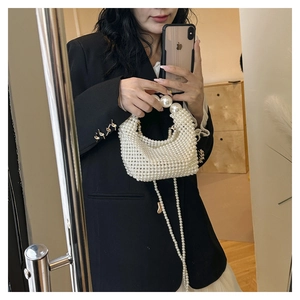 Detail der handgewebten weißen Perlenhandtasche mit großem Perlengriff und Umhängekette