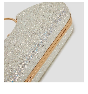 Macro shot of glittering silver sequins on a luxury evening clutch bag with gold frame