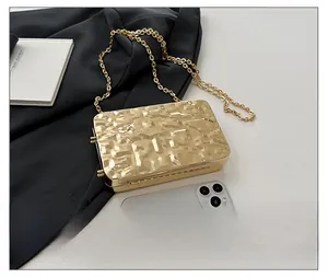 Golden acrylic evening bag with ice-crack texture and metallic chain next to a smartphone