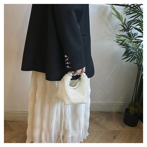Detail einer handgefertigten weißen Perlenhandtasche mit großen Akzenten am Griff