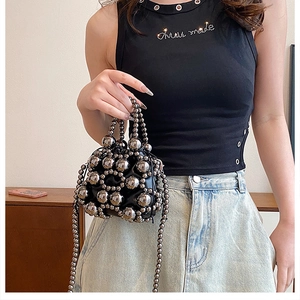 Detail of black mini bucket bag with silver studded beads and beaded handle on a model