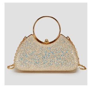 Close-up of champagne gold evening bag with glitter sequins and gold ring handle