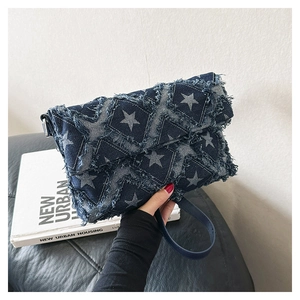 Detail of blue denim shoulder bag with white star pattern and frayed edge fringe