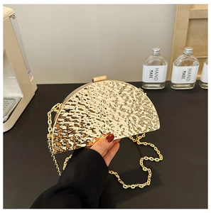 Detail of golden semi-circle evening clutch with hammered metal texture and chain strap