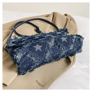 Detail of blue denim crossbody bag with white star patterns and frayed fringe edges