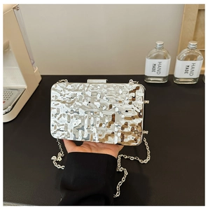 Close-up of silver acrylic evening bag with modern ice-crack texture and chain