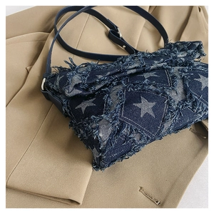 Detail of denim crossbody bag with white star pattern and stylish frayed fringe edges