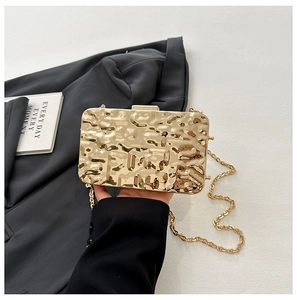 Macro view of golden shell evening bag featuring luxury hammered metal texture and chain