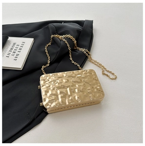 Macro detail of golden hammered texture on rectangular hard shell clutch evening bag