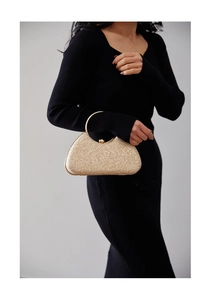 Detail of glitter evening clutch featuring a gold metal round handle and kiss-lock closure