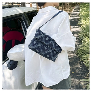 Outdoor shot of a denim crossbody bag with white stars and frayed edge detailing