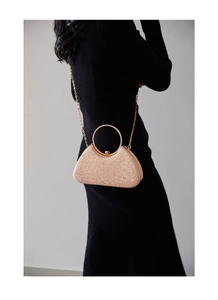Champagne glitter evening clutch bag featuring a gold round handle on a black dress