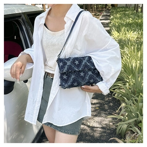 Detail of blue denim star pattern crossbody bag with vintage frayed edges and leather strap