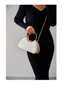 Close-up of silver sequin evening bag with gold ring handle and metal chain strap