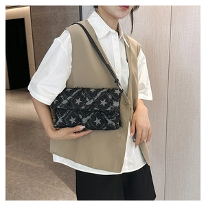 Detail of black denim crossbody bag featuring star prints and quilted frayed edges