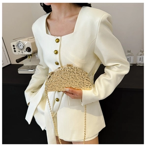 Close-up of golden shell-shaped evening bag with hammer texture worn by a model
