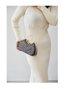 Detailed close-up of a half-moon evening bag with black and gold glitter and metal handle