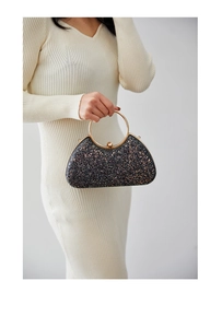 Detail showing the golden ring handle and black sequin finish of the evening clutch bag