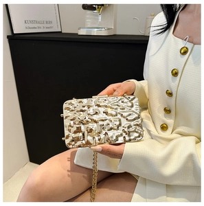 Detail of gold acrylic shell clutch featuring a unique ice crackle texture and metal chain