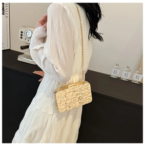 Detailed view of golden mirror evening bag with water ripple texture and chain strap