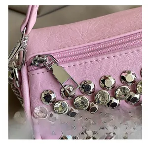 Detailed close-up of smooth metal zipper and sparkling rhinestone studs on pink PU bag