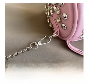 Detail of durable silver lobster clasp and metal chain on pink studded cylinder bag