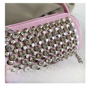 Macro detail of pink cylindrical bag featuring silver rhinestones and chain strap