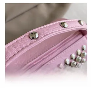 Detailed close-up of pink leather cylinder bag with polished silver metal rivets