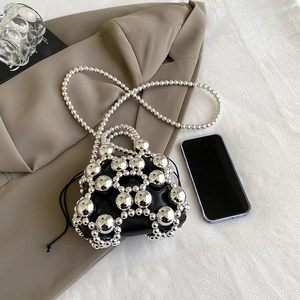 Mini silver beaded crossbody bag with black inner pouch on brown suit jacket background