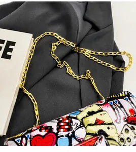 Detail of trendy pop art graffiti bag with gold chain strap on a blazer background