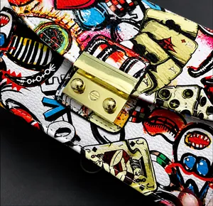 Detail of graffiti crossbody bag featuring gold clasp and lychee grain texture