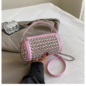 Pink cylindrical bag detail with silver rhinestones and chain strap held by hand