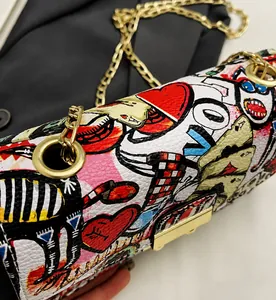 Detail of graffiti print small bag featuring gold chain strap and large metal clasp buckle