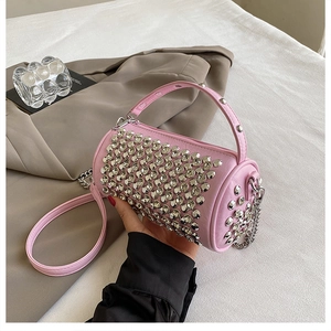 Detail of pink cylinder bag featuring silver studs and metal chain shoulder strap