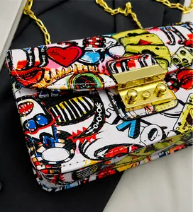 Close-up of graffiti print chain bag showing litchi texture and gold metal push lock