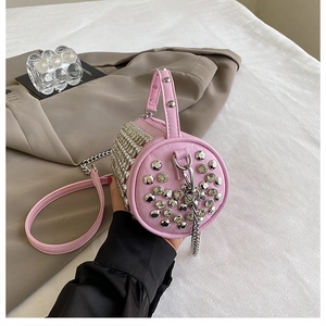Macro shot of pink cylindrical rhinestone bag featuring silver studs and metal chain strap