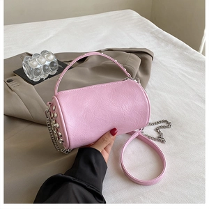 Detailed view of pink cylindrical barrel bag with silver studs and chain strap handle