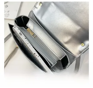 Detail view of the silver crossbody bag showing the golden zipper and interior layers
